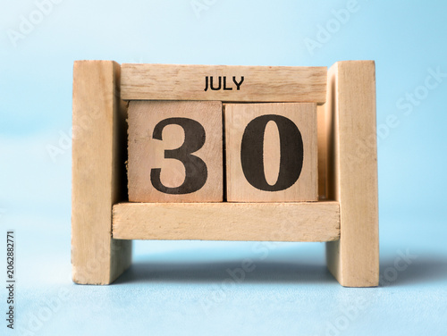Foto A wooden block calendar for July thirtieth on a light blue background