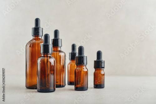 Amber glass dropper bottles of different sizes arranged in ascending order from smallest to largest on light background.