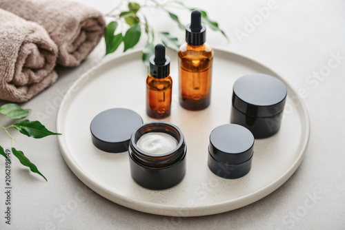 Natural skincare and beauty treatment concept with amber glass cosmetic containers arranged on a round tray.