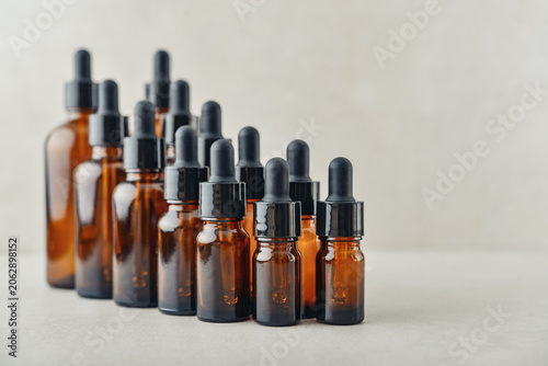 Amber glass dropper bottles of different sizes arranged in ascending order from smallest to largest on light background.