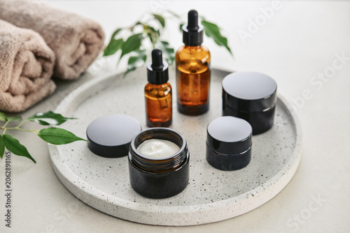 Natural skincare and beauty treatment concept with amber glass cosmetic containers arranged on a round tray.