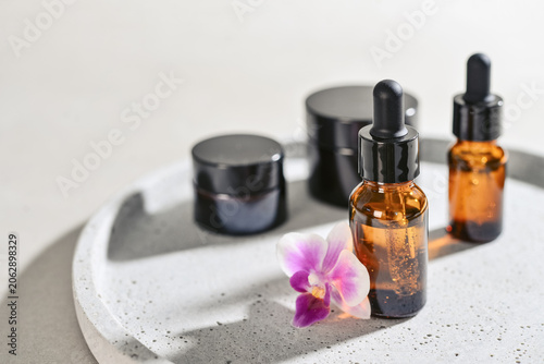 Natural skincare and beauty treatment concept with amber glass cosmetic containers arranged on a round tray.