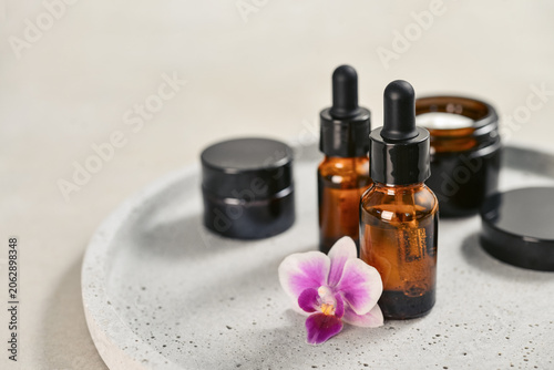 Natural skincare and beauty treatment concept with amber glass cosmetic containers arranged on a round tray.