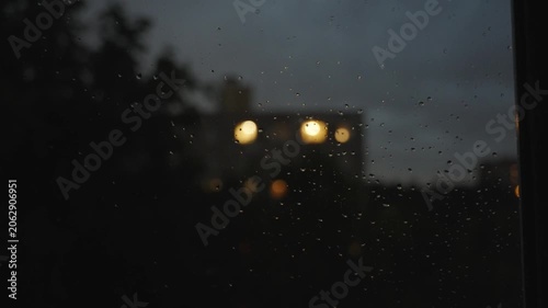 View from the window at night during rain and lightning. Raindrops on the window