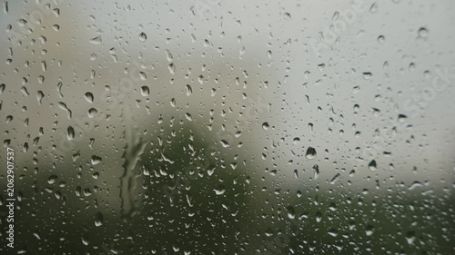 Large raindrops on the window during the rain against the background of the city