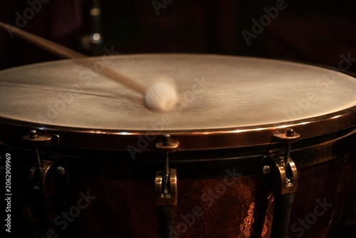 Timpani drumhead with blurred mallet impact and deep vibration.