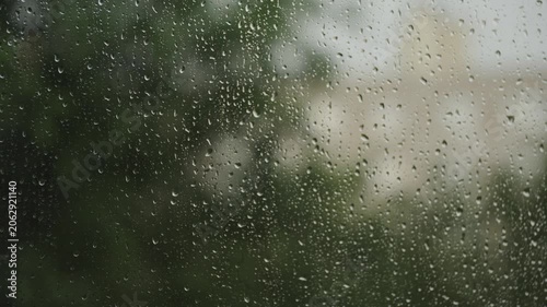 Large raindrops on the window during the rain against the background of the city