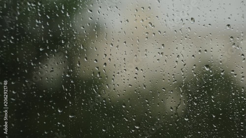 Large raindrops on the window during the rain against the background of the city