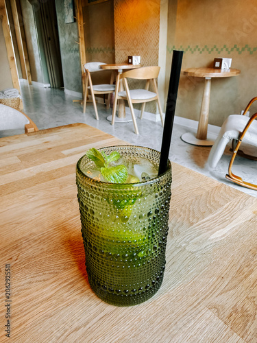 Refreshing mint lime drink in a green textured glass at a cozy cafe