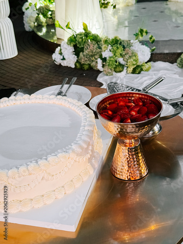 Elegant wedding reception dessert table with a white cake and fresh strawberries