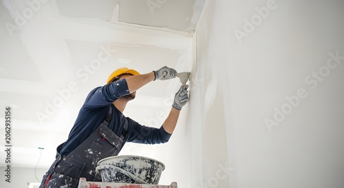 Professional worker applying plaster to a wall during home renovation, ensuring a smooth finish for painting.