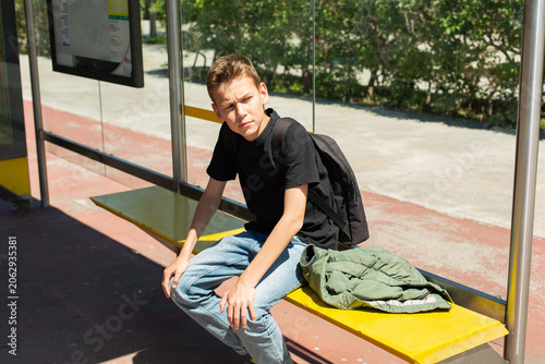 Teenager waiting the bus at the stop in the city