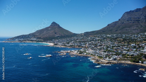 Aerial stock image of Camps Bay, Bakoven and Lions Head,  Cape town Coastline camera approaching from the sea over the beach and neigbourhood on a summer day