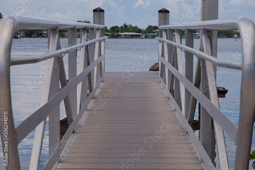 Schilderij op canvas Pelican Perched on Dock Over Calm Waterfront With Pier, Reflections and Coastal Homes Crisp Park in St