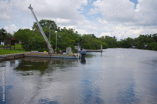 Foto Work Boat Docked on Quiet Canal Near Mangroves Under Cloudy Sky With Reflections Crisp Park in St