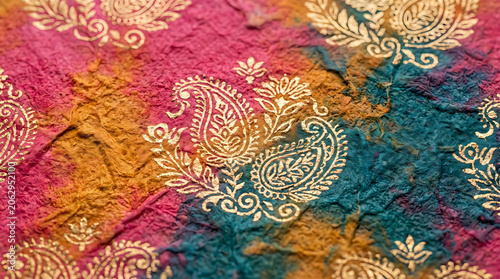 Textured tie dye paper with gold paisley foil print close up
