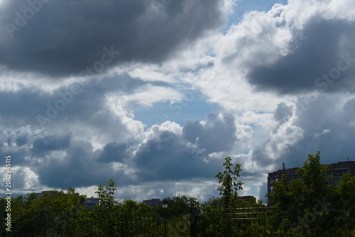 Cumulus clouds over trees and houses