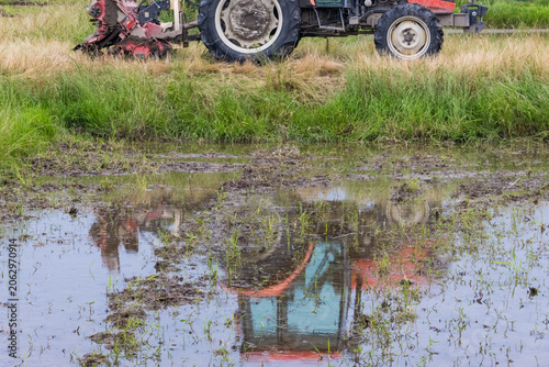 Agricultural tractor reflected in flooded rice field
