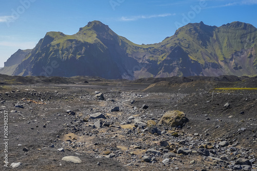 Canvas Print Rugged volcanic landscape with rocky terrain and distant green mountains under a