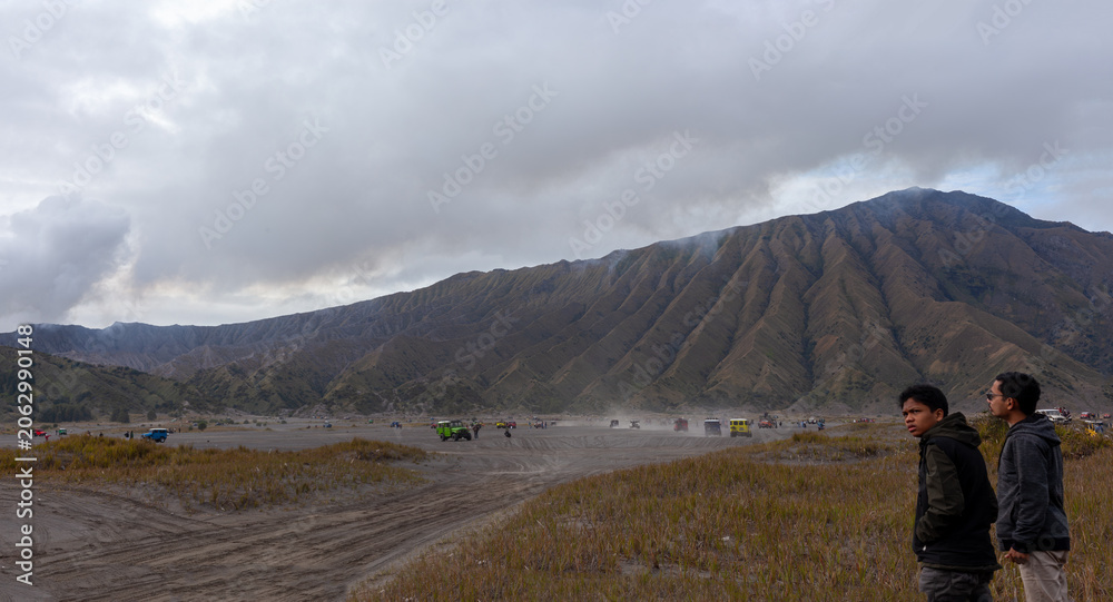Fototapeta premium Tourists enjoying the vast and dramatic volcanic landscape of Mount Bromo Tengger Semeru, Indonesia.