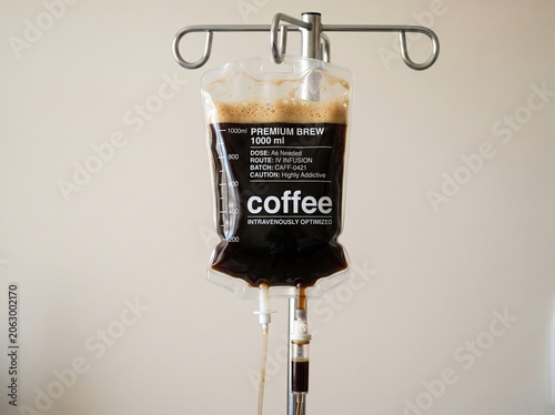 Humorous concept of a medical IV drip bag filled with dark frothy coffee with the text 