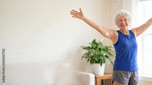 Senior woman with glucose monitor sensor on arm celebrating healthy life. Happy elderly lady managing diabetes with continuous monitoring technology. Active lifestyle and wellness concept.