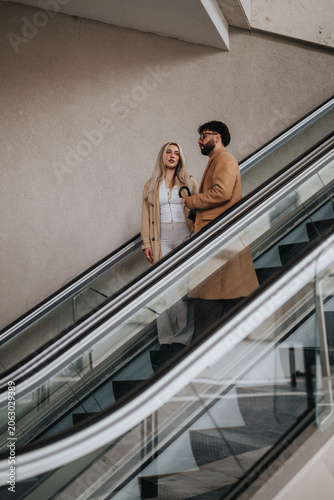 Canvas Print A business couple rides an escalator in a modern building