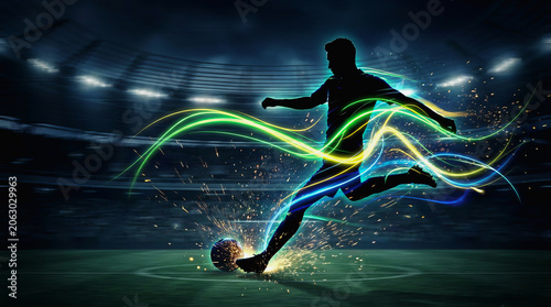 Soccer player silhouette kicks ball with colorful light trails in stadium at night