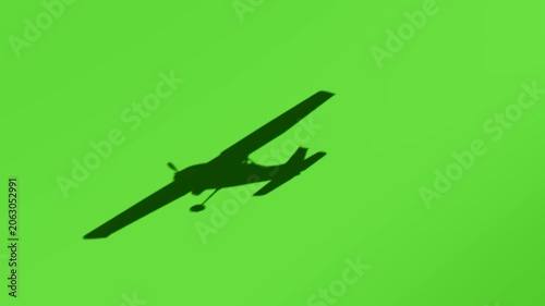 Silhouette of a small propeller plane flying against a vibrant green background, motion of aircraft in flight