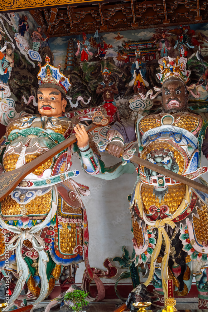 Fototapeta premium Two monumental, highly detailed statues of the Buddhist Heavenly Kings (Lokapala) guarding a temple hall at the Daxingshan Temple complex in Xi'an, Shaanxi Province, China,