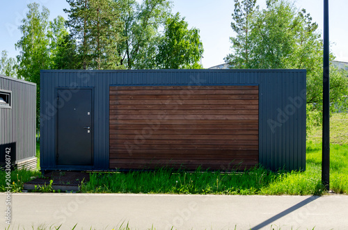 modern container cabin stands on green grass near paved road. this container cabin provides flexible temporary workspace. modular container cabin offers smart housing solution for site.