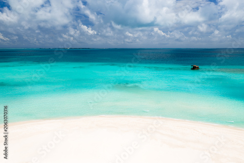 Foto White sand arcs into shallow turquoise water deepening to sapphire