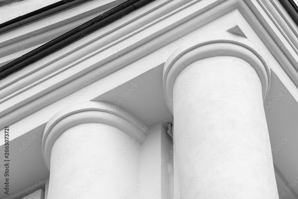 Naklejka premium White classical building facade with round pillars and pediment showcasing architectural detail in a black and white composition, emphasizing style, texture, and historic design