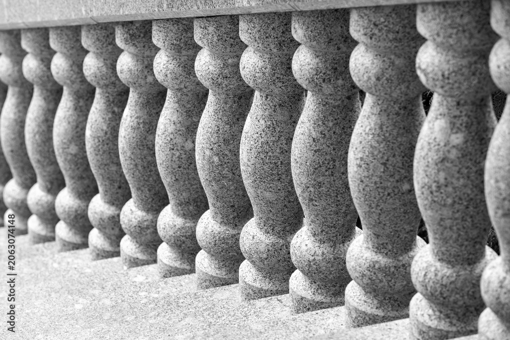 Naklejka premium Elegant stone balustrade featuring repeating turned granite columns that create rhythmic texture and symmetry in black-and-white architectural photography