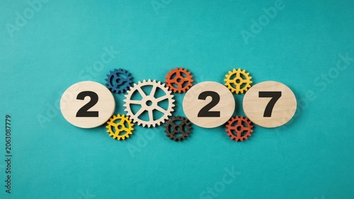 Wooden discs with number 2027 and colorful gears on teal background