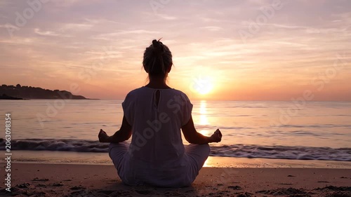 Woman meditating in lotus position on beach at sunset with serene ocean view and warm colors.
