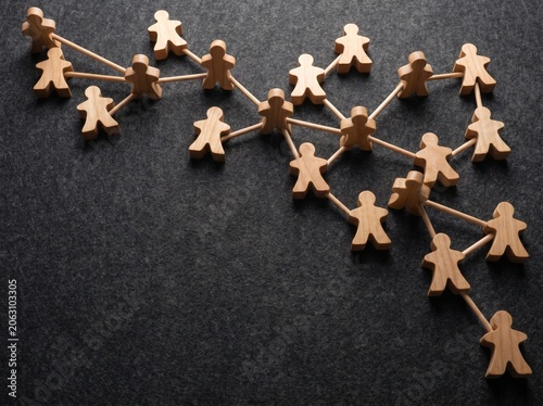 Wooden peg dolls arranged in interconnected lines and clusters evoke a visual representation of global communication networks, team building, social connections, and collaborative efforts
