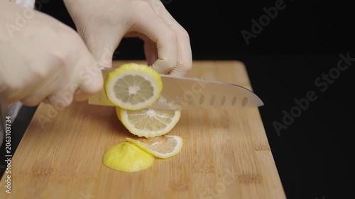 Hands slicing lemon on a bamboo cutting board