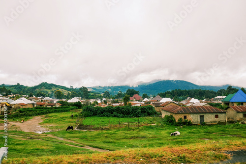 Scenic Rural Landscape of Mbeya Town, Tanzania with Houses and Lush Green Hills Under a Cloudy Sky
