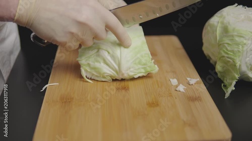 Hands shredding cabbage on a cutting board