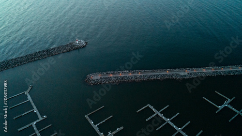 Foto A striking top-down drone photograph looking down at the stone breakwater walls and illuminated promenade pier protecting empty marina boat slips in the dark, calm waters of Bronte Harbour at dawn