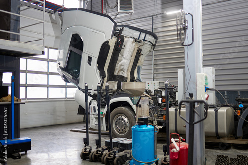 This image features an oil change machine strategically placed near a truck with a white cab in an active car service area, illustrating essential automotive repair tools and facilities.