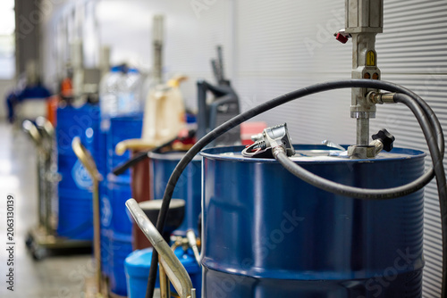A professional car service garage featuring a neat row of blue oil barrels. The barrels are organized and ready for use, reflecting a clean and efficient automotive environment.