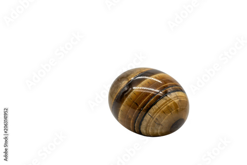 A polished oval tiger eye gemstone with brown and gold banded patterns, featuring a smooth reflective surface resting on a solid