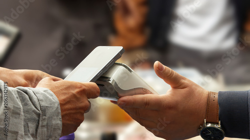 Close-up of a customer paying with a smartphone via contactless terminal at the Taste of Italy street food festival in Karlin Prague. Modern cashless economy, digital wallet, and fast outdoor service.