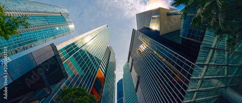 фотографія Low-angle view of modern glass skyscrapers with sunlight reflections