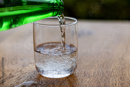 Pouring sparkling water from green bottle into glass