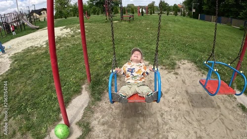 Child on swing at playground with parent hand