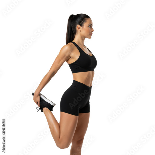 Young athletic woman with dark hair in black activewear stretching one leg gracefully in a transparent studio, exuding calm focus and athletic determination