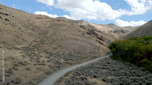 Aerial views of a rocky hillside just outside of Winnemucca Nevada the drone follows a road leading to the top of the mountain.